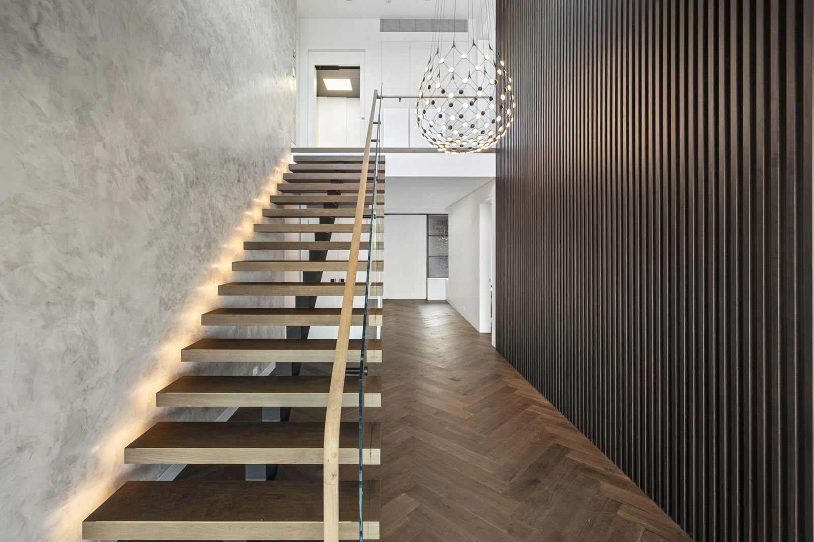 Floating oak stair against polished plaster and dark timber battens
